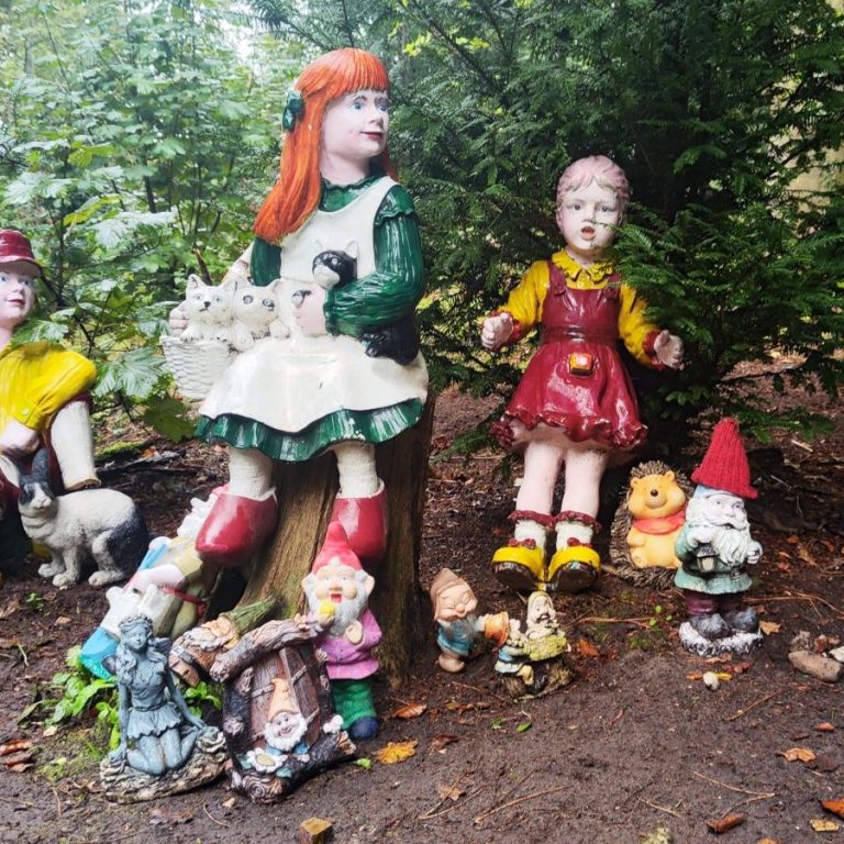 Twee levensgrote beelden van kinderen met een groepje tuinkabouters eromheen.